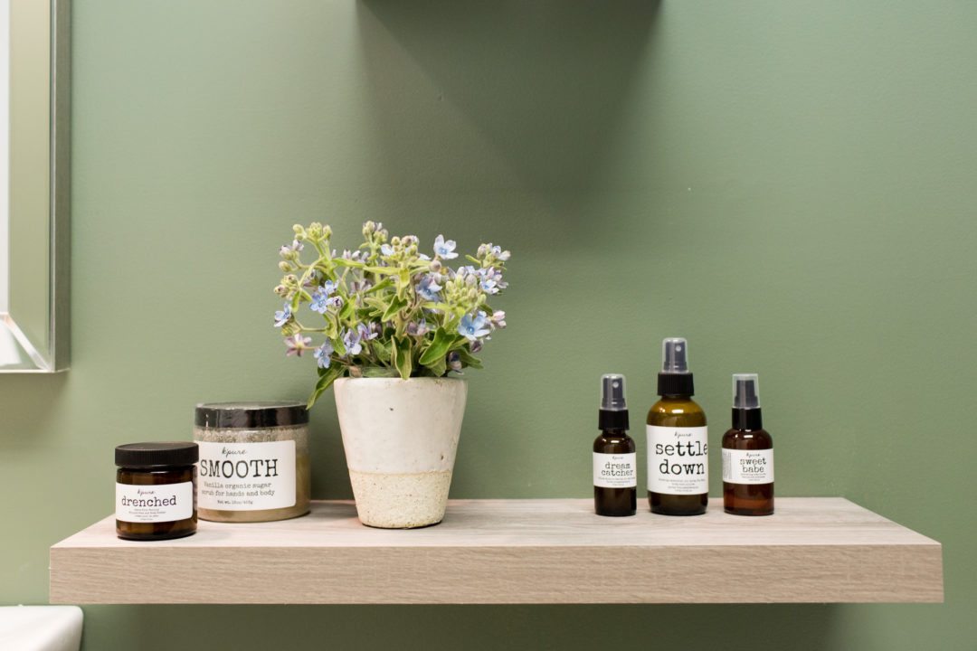 display of sprays and scented candles and a potted plant against a green painted wall at Mamas For Mamas charity